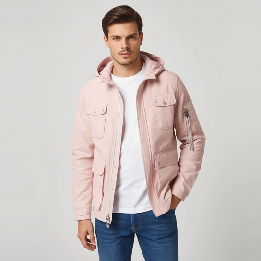 Mann trägt eine rosa Jacke mit Kapuze, Reißverschluss und Taschen zu einem weißen T-Shirt und blauen Jeans vor hellem Hintergrund.   